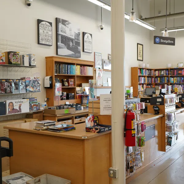 Interior view of a bookstore showing wooden counters, shelves with books and items, and a bestsellers sign.