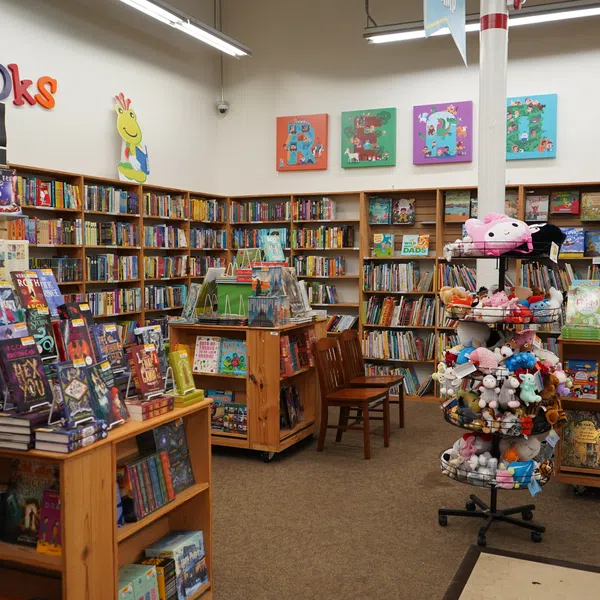 Children's section of a bookstore with colorful decorations, bookshelves, toys, and stuffed animals on display.