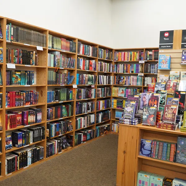 Corner of bookstore with wooden shelves filled with books and a display table featuring bestsellers.