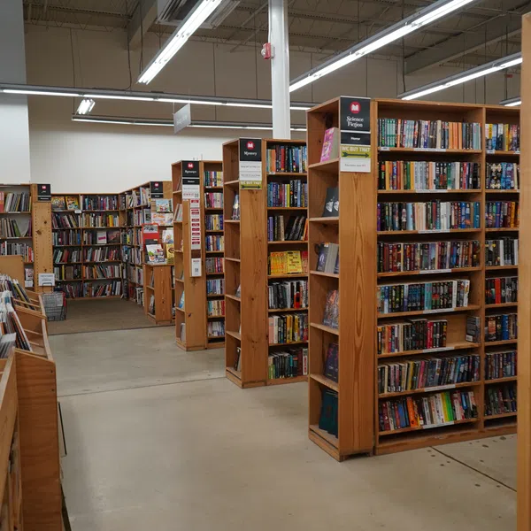 Interior of a bookstore with wooden shelves filled with books and a clean, well-lit pathway.
