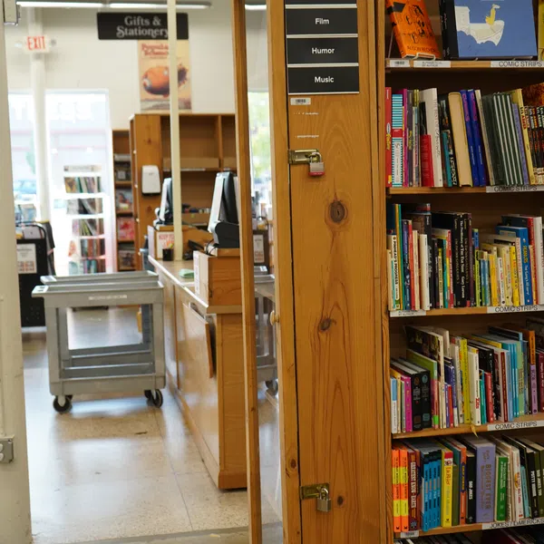 Bookshelf in bookstore featuring performing arts books on film, humor, and music near checkout counter.