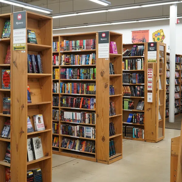 Interior of bookstore showing wooden shelves filled with mystery books and novels under bright lighting.