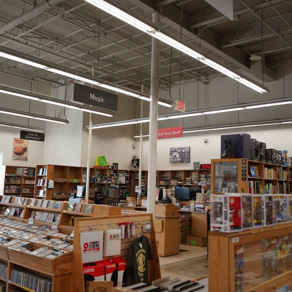 Interior of a bookstore featuring shelves with music CDs, books, and collectibles under bright ceiling lights.
