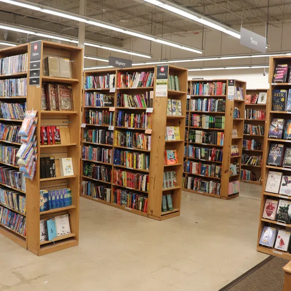 Interior view of a library with wooden bookshelves filled with books under bright fluorescent lights