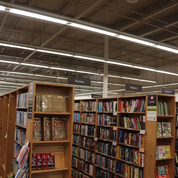 Interior of a bookstore with wooden shelves filled with books categorized by fiction, history, and religion sections.