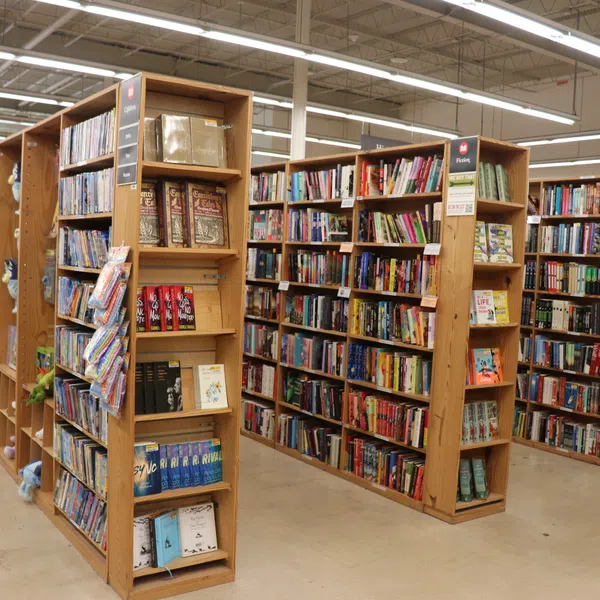 A spacious bookstore interior with tall wooden shelves filled with various books and bright overhead lighting.