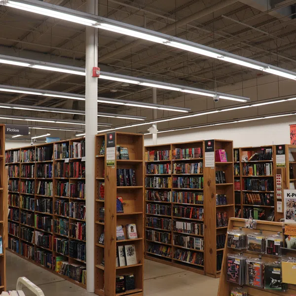 Interior of a bookstore with tall wooden shelves filled with books and a section for vinyl records and K-pop merchandise.