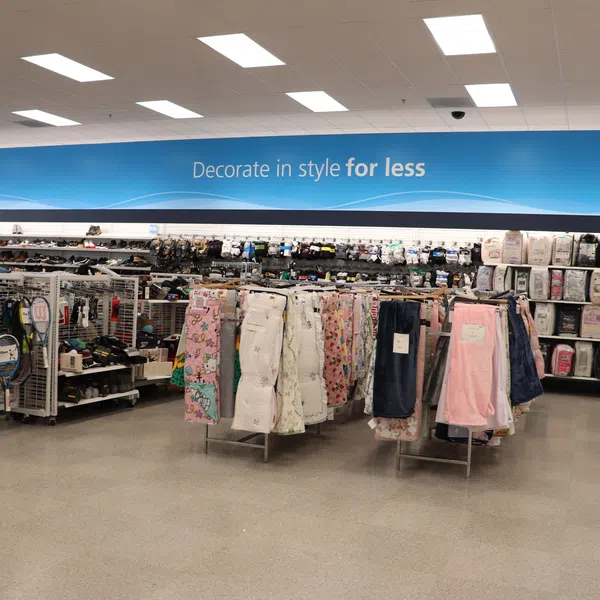 Interior of a home goods store with bedding, towels, and decor under a sign reading 'Decorate in style for less'