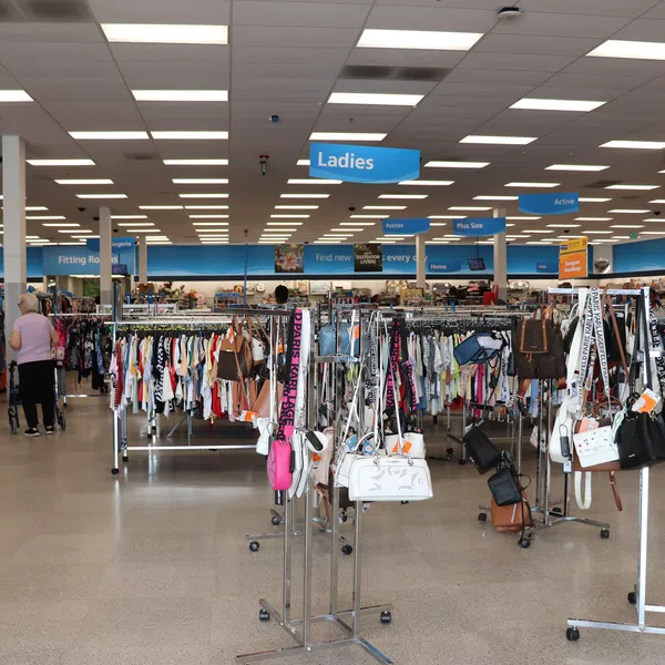 Spacious women's clothing store section with racks of clothes, handbags, and shoppers browsing