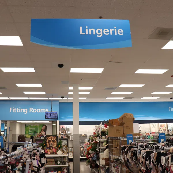 Lingerie section in a retail store with racks of clothing and fitting rooms visible under bright fluorescent lights.