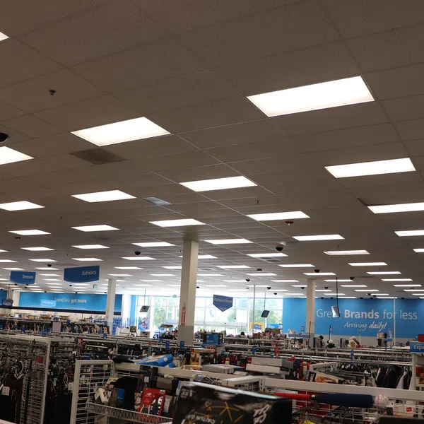 Interior of a large retail store with bright ceiling lights and clothing racks organized by categories.