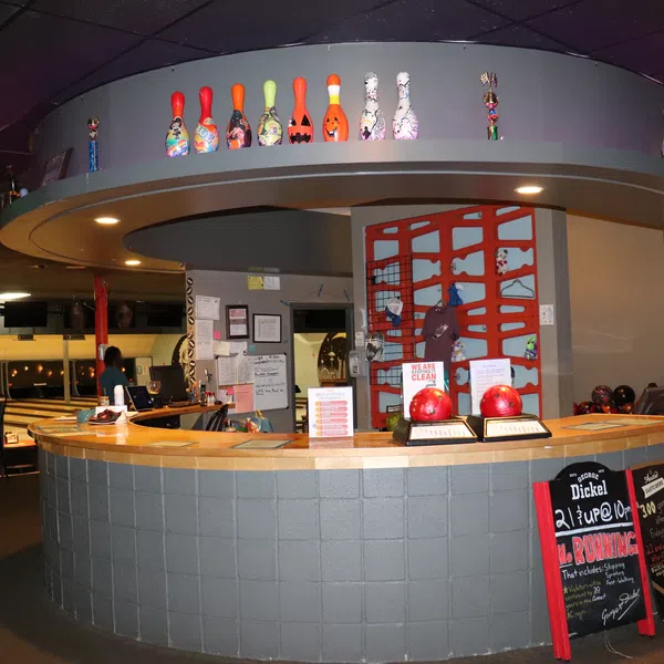 Reception desk at bowling alley with colorful bowling pins decoration and seating area in background