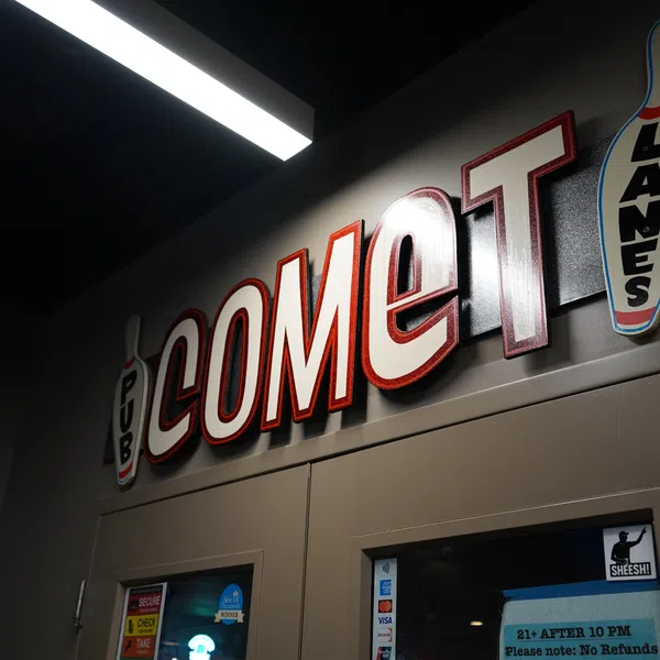 Comet Lanes bowling alley sign above double doors in a dimly lit hallway with bowling pin graphics.
