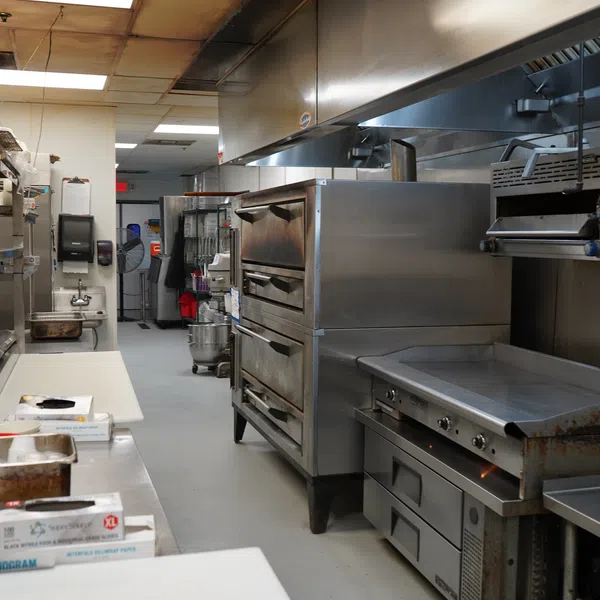 Commercial kitchen with stainless steel ovens, griddles, prep tables, and kitchen equipment in a clean setting