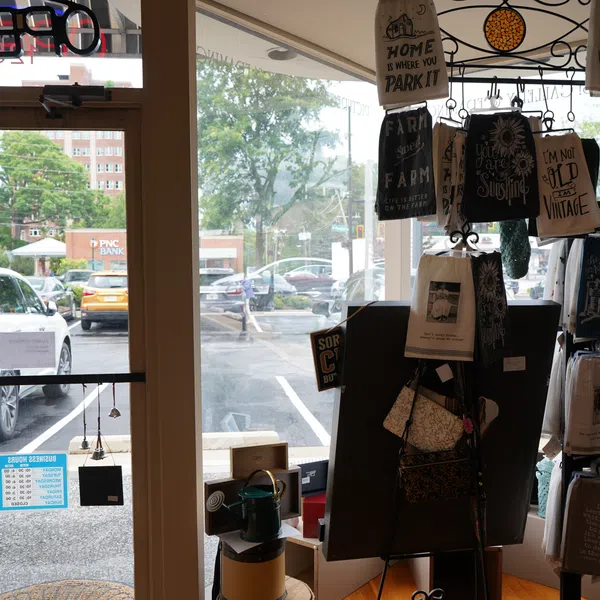 Gift shop interior featuring hanging and displayed decorative towels by a glass door with parking lot view outside