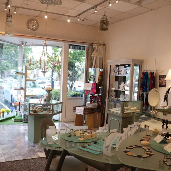 Bright jewelry store interior with display cases, necklaces, earrings, and decorative lighting near glass storefront.