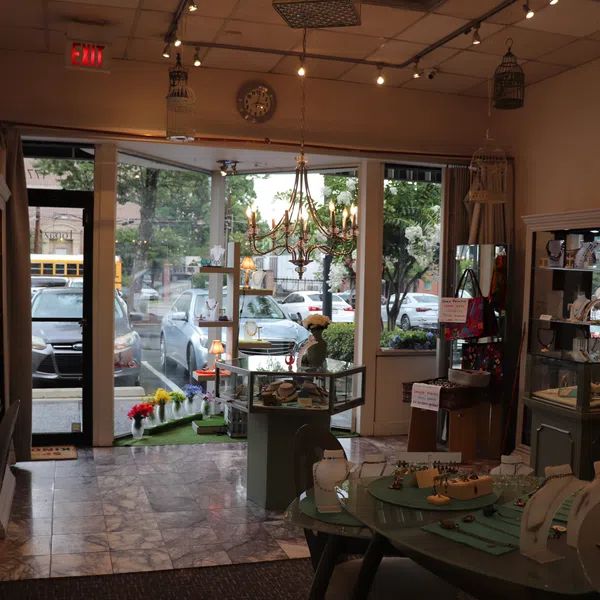 Jewelry store interior with display cases, chandelier, and large windows showing parked cars outside on a sunny day