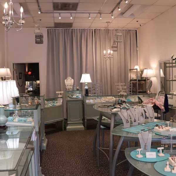 Interior view of a bright jewelry store with multiple display cases and elegant lighting fixtures.