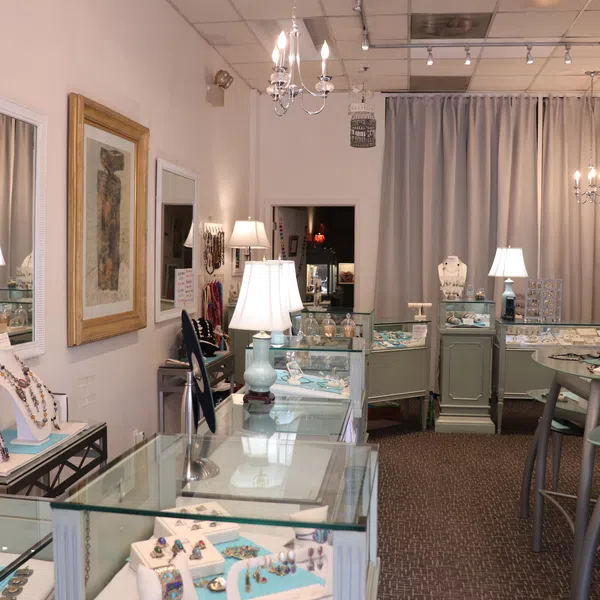 Interior of a jewelry store with glass display cases, table displays, elegant lighting, and framed wall art.