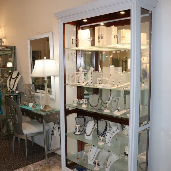 Brightly lit glass display cases filled with various necklaces and jewelry in an elegant boutique.