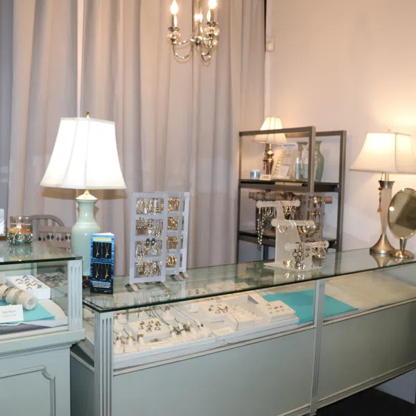 Jewelry store display with bracelets, rings, earrings in glass cases and soft lighting lamps.