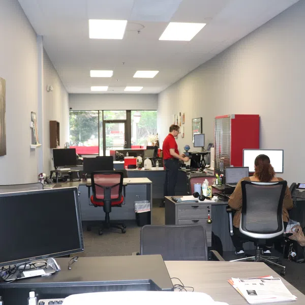 Modern office space with computers, employees working, and natural light from large windows