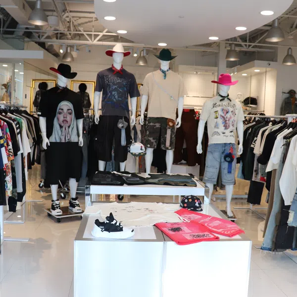 Modern clothing store interior with mannequins dressed in casual attire and racks of various apparel.