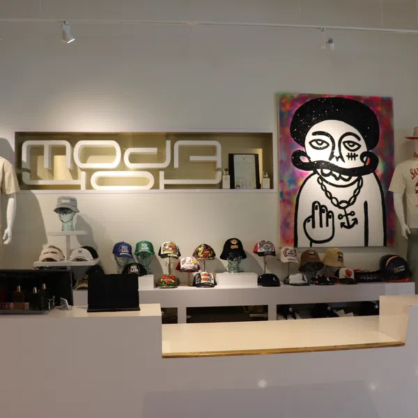 Modern fashion store interior with mannequins, graphic art, and various hats displayed on white shelves.