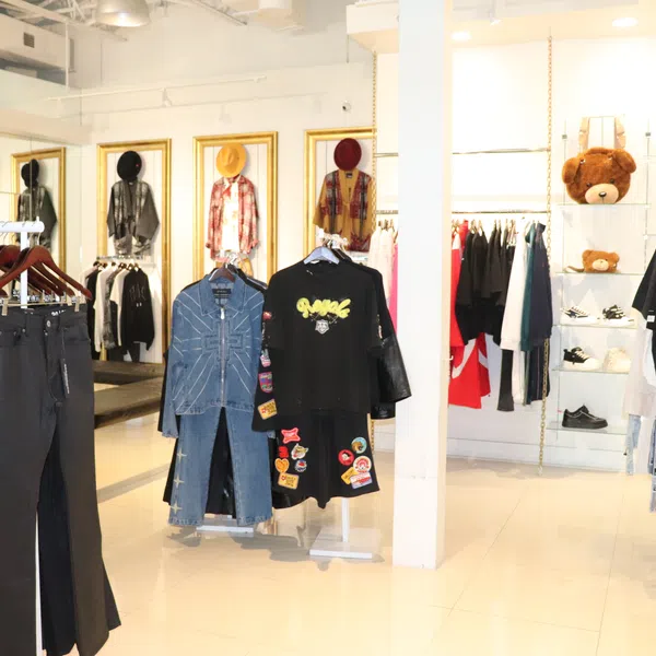 Modern clothing store interior with racks of jeans, jackets, graphic tees, and apparel on display.
