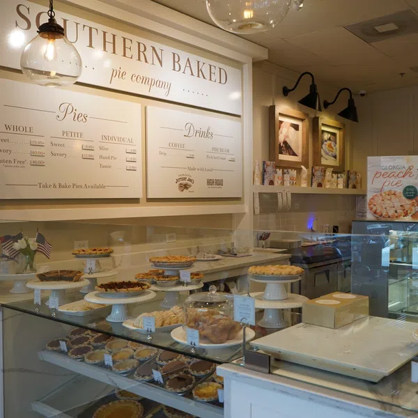 Interior of Southern Baked Pie Company showcasing various pies displayed on white cake stands and menu above.