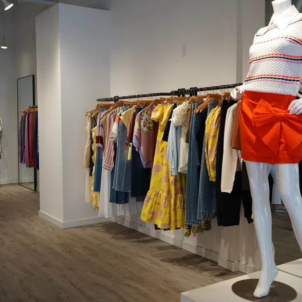 Modern clothing store interior with colorful dresses on racks and a mannequin in a red skirt and striped top