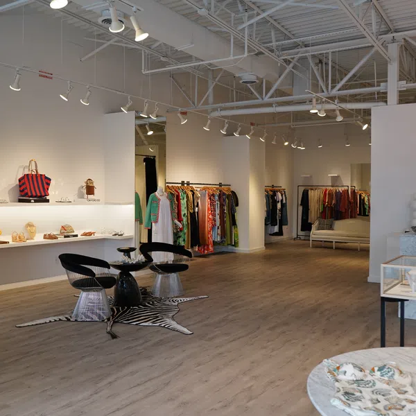 Modern boutique interior with clothing racks, mannequins, shoes, accessories, and stylish seating area.