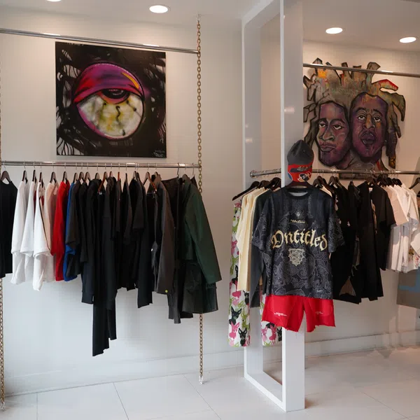 Modern clothing store interior with hanging apparel and vibrant graffiti-style artwork on walls.