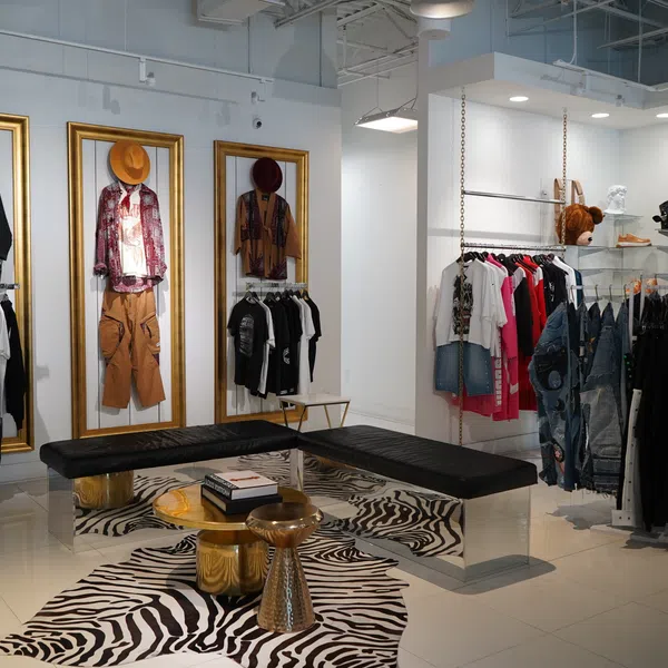 Modern boutique interior with stylish clothing displays, framed outfits, black seating, and zebra print rug.