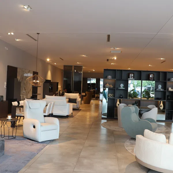 Modern furniture showroom with white recliners, cozy chairs, decorative shelving, and warm lighting.