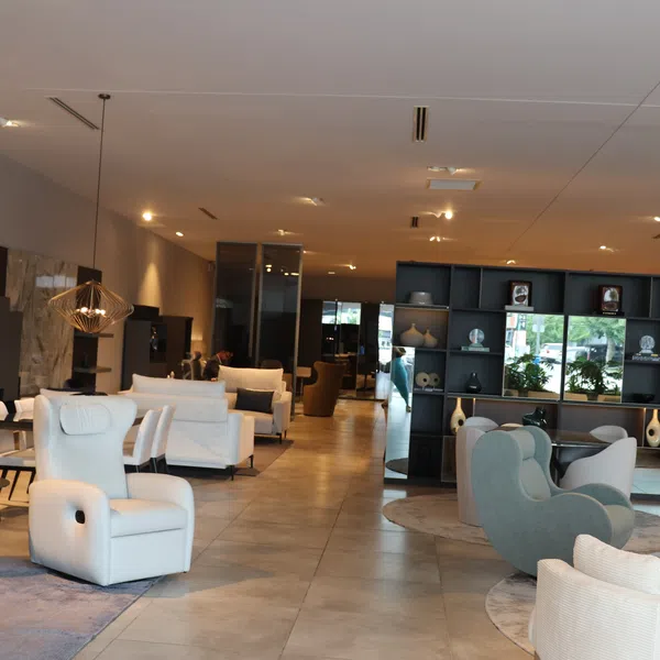 Modern furniture showroom with armchairs, sofas, decorative shelves, and ambient lighting in a spacious showroom.