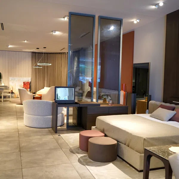 Modern spacious bedroom and living area with neutral tones, comfortable furniture, and elegant decor lighting.