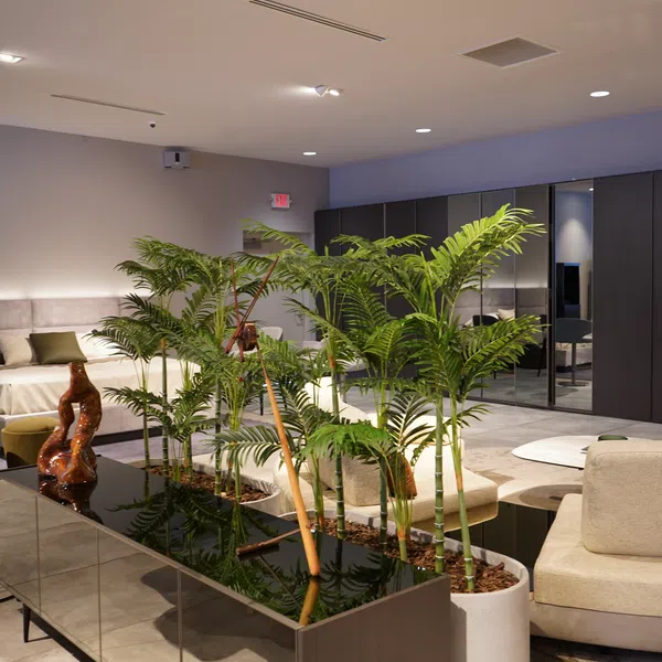 Modern living space with indoor plants, beige furniture, armchair, and dark wardrobe with mirrored doors