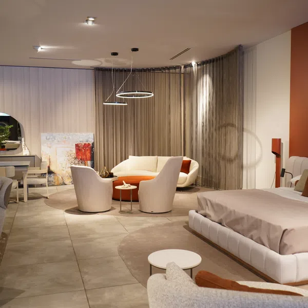 Modern living room and bedroom combination with neutral tones, circular seating area, and minimalist decor.