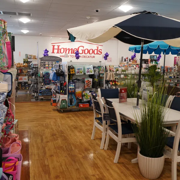 Indoor view of HomeGoods store featuring outdoor furniture, umbrellas, home decor items, and wooden flooring