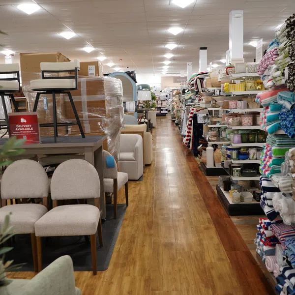 Aisle in a home goods store with furniture on the left and shelves of blankets and textiles on the right