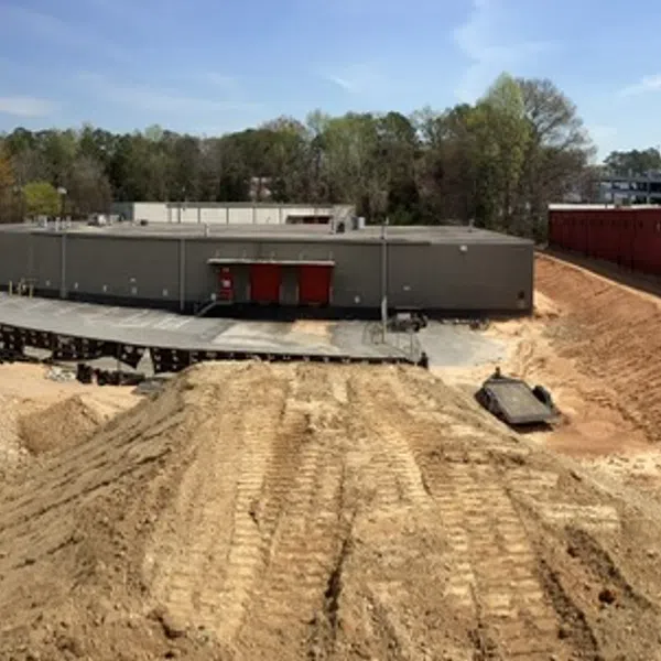 Panoramic view of large construction site with cleared earth, industrial buildings, and clear sky during daytime