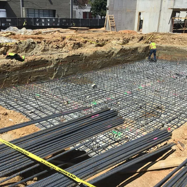 Construction site with steel rebar grid foundation and workers preparing for concrete pouring