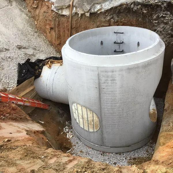 Large concrete stormwater drainage pipe section installed in an excavation site with construction equipment nearby