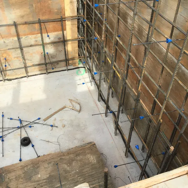Concrete foundation with steel rebar grid and plastic spacers in early stage construction site.