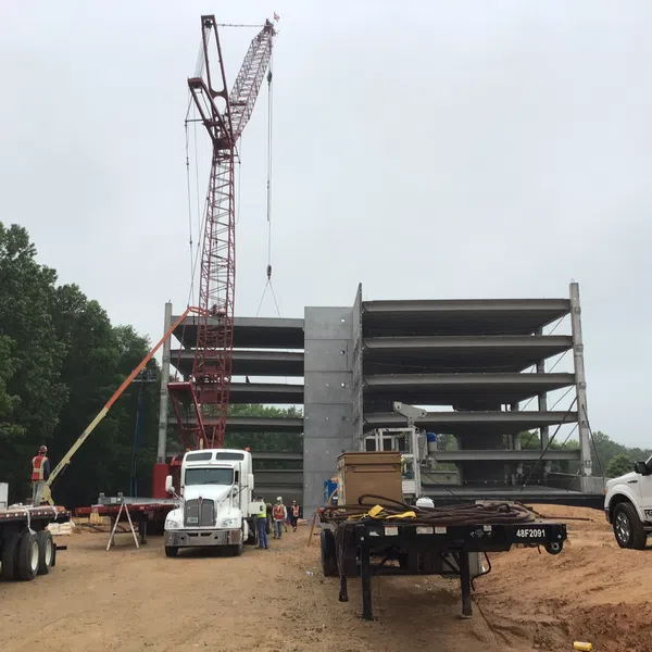 Construction site with crane lifting materials near multi-story concrete building framework on cloudy day