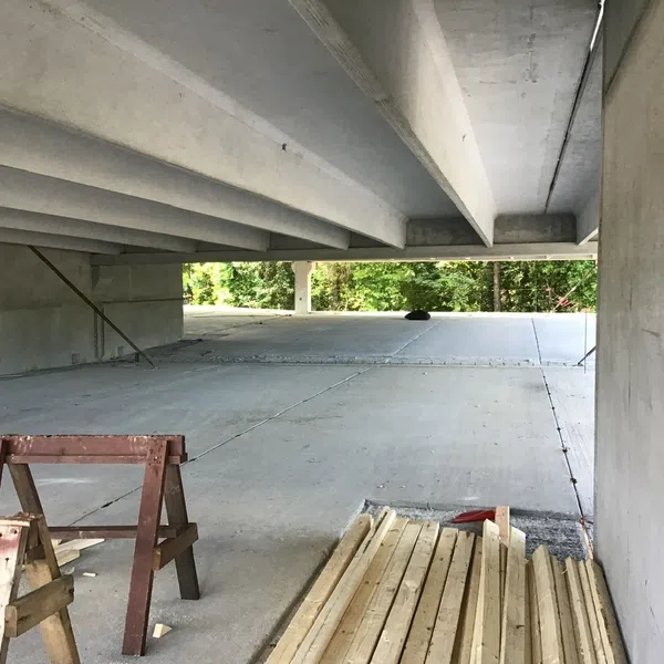 Empty concrete parking garage under construction with wooden planks and saw horses on floor