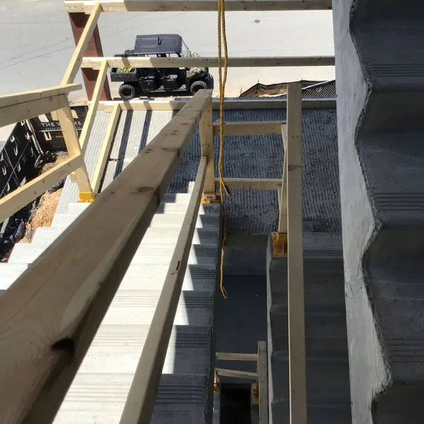Top view of construction site showing wooden railings and concrete stairs with a small vehicle at the bottom.