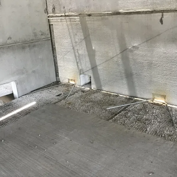 Concrete floor under construction with exposed rebar and unfinished walls in a building site.