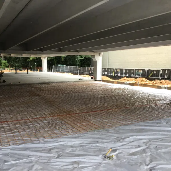 Under-construction parking garage with concrete pillars and steel reinforcement grid for new concrete floor slab.